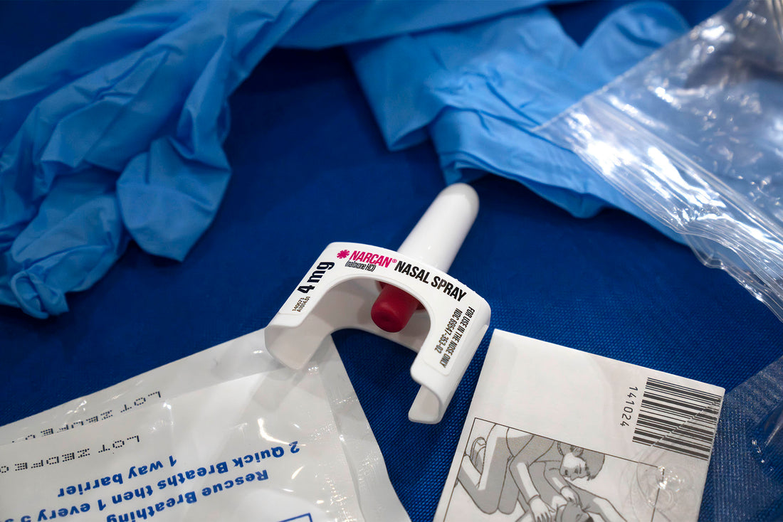 Narcan nasal spray and medical gloves on a blue surface, illustrating affordable life-saving medication available from Discount Narcan.